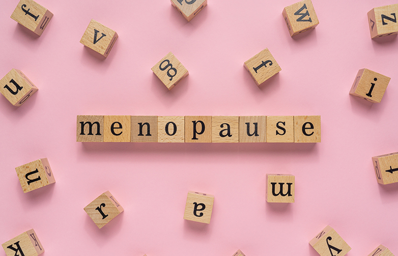 Menopause word on wooden block. Flat lay view on light pink background.