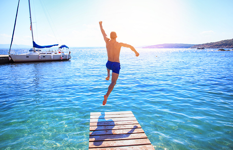 Cheerful man jumping into water