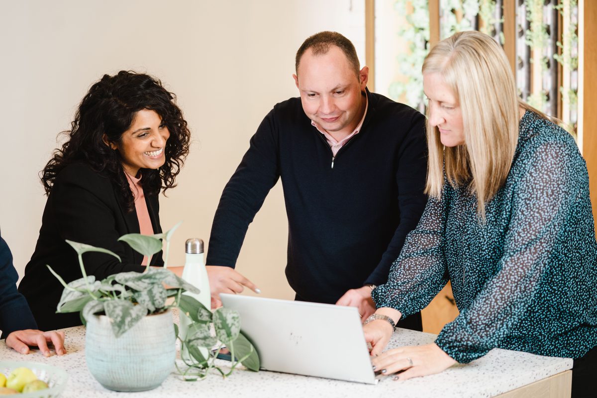 Diverse group from EBP team, in kitchen, reviewing a piece of work over a laptop