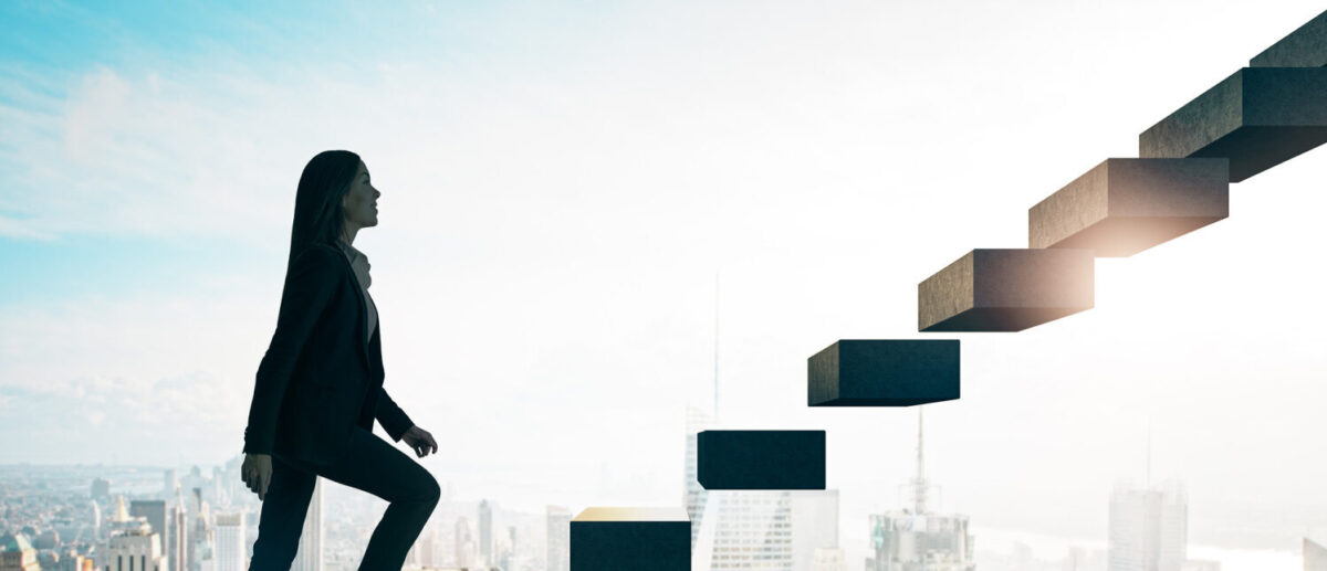 Road to success concept with businesswoman going up the stairs on sunny megapolis city background. Ascending the career ladder: Why aren’t there more female leaders in the finance sector?